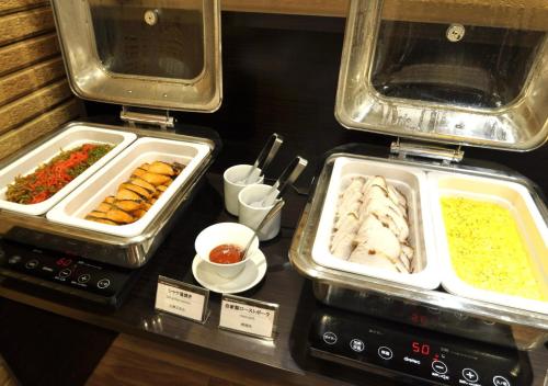 un buffet avec plusieurs plateaux de nourriture sur une table dans l'établissement APA Hotel Nagoya Sakaeekimae Excellent, à Nagoya