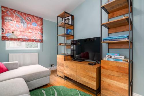 a living room with a tv and a wooden entertainment center at GuestReady - Family-Friendly Flat in Battersea in London