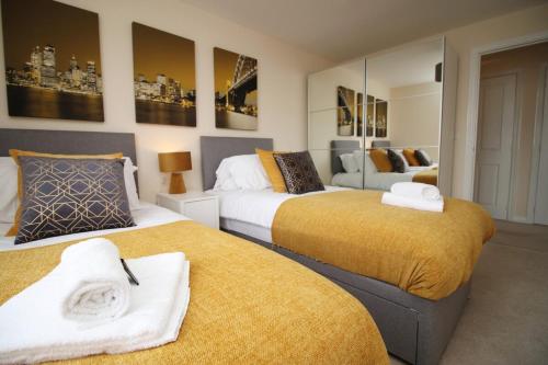 a bedroom with two beds with yellow blankets at Upper Millennium by Tŷ SA - Free Parking in Newport