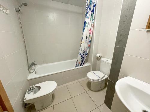 a white bathroom with a toilet and a sink at Apartamentos Playa de Benicarló 3000 in Benicarló