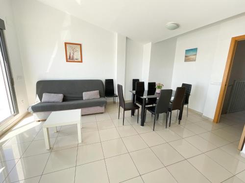 een woonkamer met een bank en een tafel en stoelen bij Apartamentos Playa de Benicarló 3000 in Benicarló