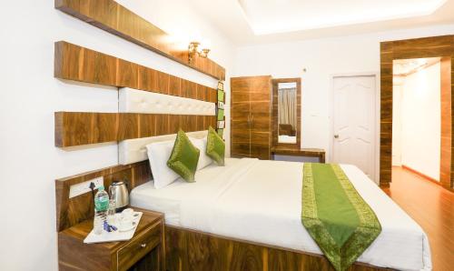 a bedroom with a large white bed with green accents at Treebo Skydale Inn & Suites With Mountain View in Ooty