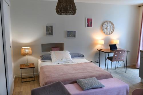 1 dormitorio con cama, mesa y reloj en Suran - 2 pers-wifi-confort, en Oyonnax