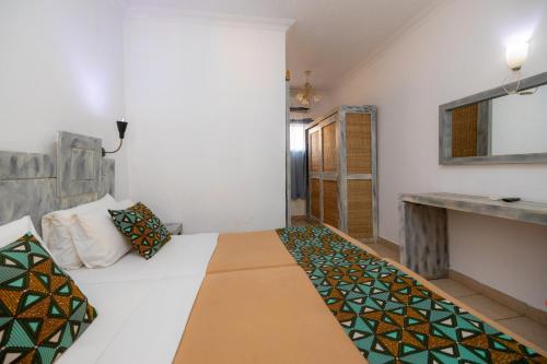 a bedroom with a white bed and a mirror at Sarges Hotel in Sere Kunda