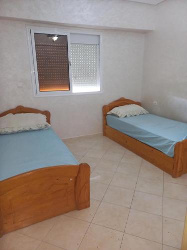 two beds in a room with a window at Dari A10 in Agadir