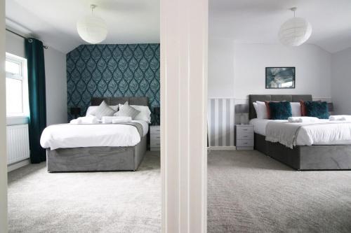 a bedroom with two beds and a wall at Willow Way by Tŷ SA in Nantgarw