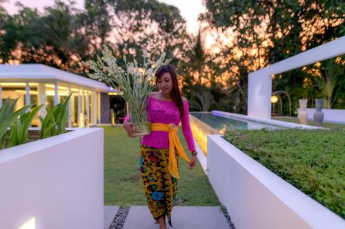 uma mulher segurando uma planta em um jardim em The Sound of Silence - Private Villa Retreat UTOPIA for LUXXE Travellers em Tanah Lot