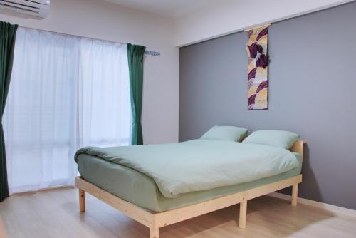 a bedroom with a bed with a green mattress at Island Stay Izumizaki Hotel in Naha