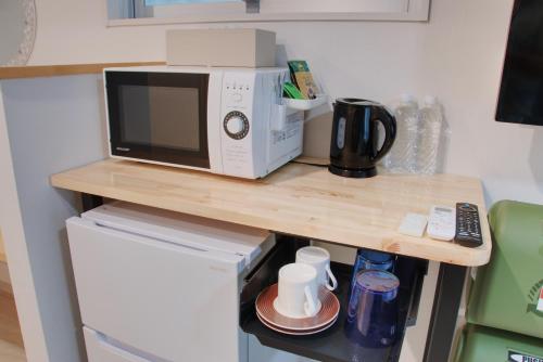 a microwave sitting on top of a counter next to a refrigerator at Island Stay Izumizaki Hotel in Naha