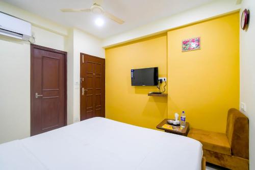 a bedroom with a bed and a tv on a yellow wall at Hotel Mahal in kolkata