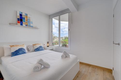 a bedroom with a large white bed and a window at GREEN AGAVE by Welcome Tenerife in Playa de las Americas