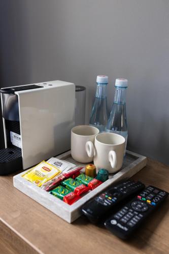 a counter with a coffee maker and two bottles of soda at Four Sisters Luxury Rooms in Siauliai in Šiauliai