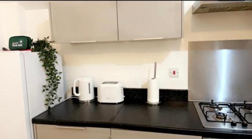 une cuisine avec des placards blancs et un comptoir noir dans l'établissement KGA7- Kazi Court, à Wakefield
