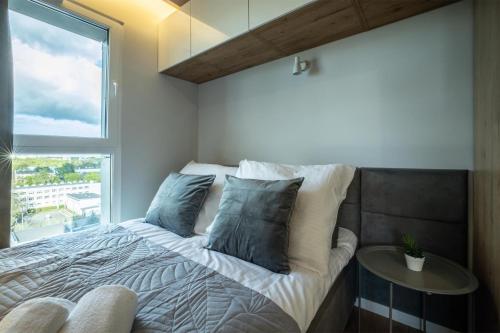 um quarto com uma cama grande e uma janela em WiguryTower Apartaments 92 em Lódź