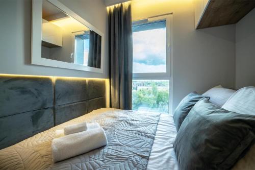 um quarto com uma cama com um espelho e uma janela em WiguryTower Apartaments 92 em Lódź