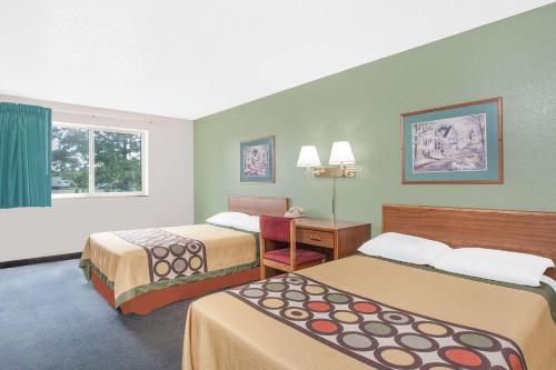 a hotel room with two beds and a desk at Super 8 by Wyndham Queensbury Glens Falls in Queensbury
