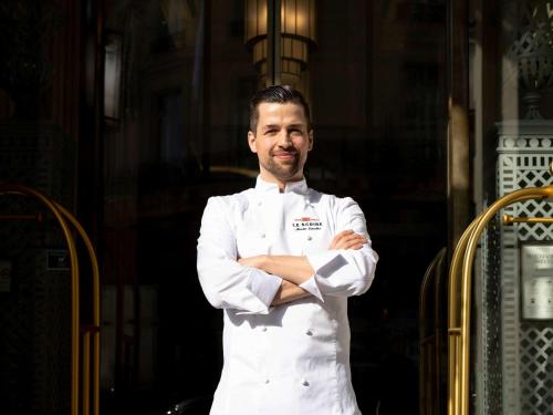 un hombre con un uniforme de chef parado con los brazos cruzados en Sofitel Le Scribe Paris Opera, en París