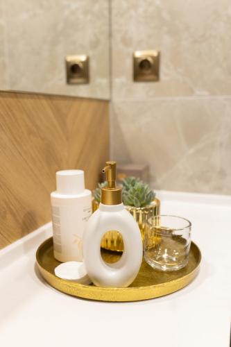 a tray with a bottle of soap and a glass at Four Sisters Luxury Rooms in Siauliai in Šiauliai