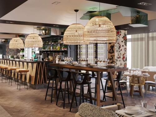 a restaurant with a large wooden bar with stools at Novotel Bordeaux Centre Ville in Bordeaux