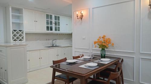 - une cuisine blanche avec une table et des chaises en bois dans l'établissement Goldmark city 3PN sang trọng, à Hanoï