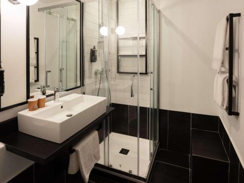 a bathroom with a sink and a glass shower at Ibis Brive Centre in Brive-la-Gaillarde