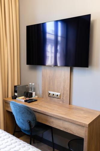 a desk in a hotel room with a television on the wall at Four Sisters Luxury Rooms in Siauliai in Šiauliai