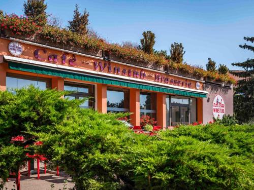 ein orangefarbenes Gebäude mit Pflanzen darüber in der Unterkunft ibis Colmar Est - Hotel Restaurant en Alsace in Colmar