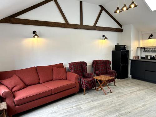 uma sala de estar com um sofá vermelho e duas cadeiras em The Dairy em Sutton