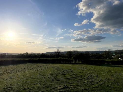 um campo de relva com o sol no céu em The Dairy em Sutton