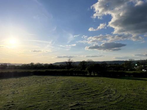 un campo de hierba con el sol en el cielo en The Dairy, en Sutton