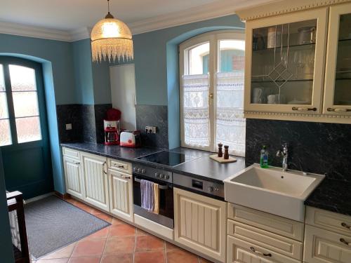Una cocina con gabinetes blancos y un fregadero. en Suite im Limonadenhaus - adults only, en Lübbenau