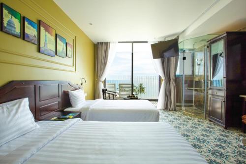 a hotel room with two beds and a balcony at Palmy Luxury Beach Phú Quốc in Phú Quốc
