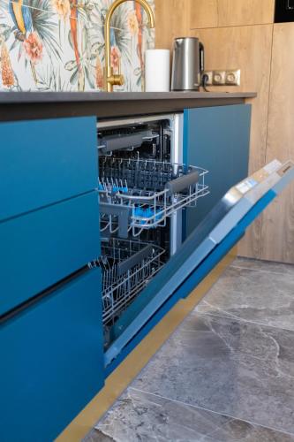 a dishwasher in a kitchen with blue drawers at Four Sisters Luxury Rooms in Siauliai in Šiauliai