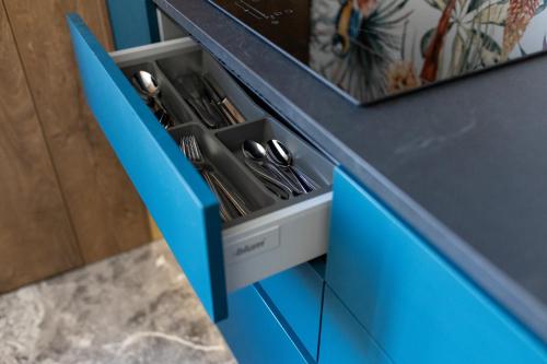 a blue cabinet with silver utensils in it at Four Sisters Luxury Rooms in Siauliai in Šiauliai