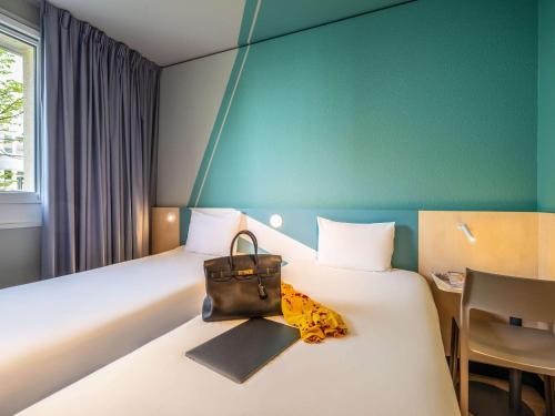 a hotel room with a bed with a purse on it at ibis budget Berlin Kurfürstendamm in Berlin