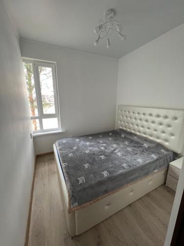 1 dormitorio con 1 cama en una habitación con ventana en Радуга Вест Квартира, en Koshkolʼ
