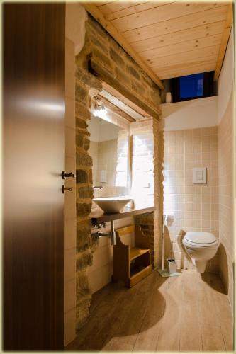 a bathroom with a toilet and a stone wall at Il Palazzo del Barone - Stanza dei Calì in Pietrapertosa