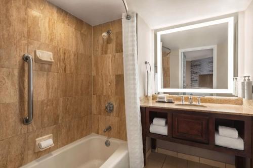 a bathroom with a tub and a sink and a mirror at Embassy Suites by Hilton Kansas City Overland Park in Overland Park