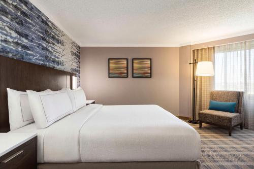 Pokój hotelowy z dużym łóżkiem i krzesłem w obiekcie Embassy Suites by Hilton Kansas City Overland Park w mieście Overland Park