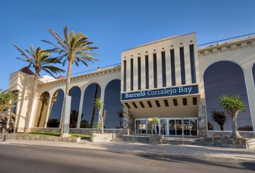 un centro commerciale con palme di fronte a un edificio di Barceló Corralejo Bay - Adults Only a Corralejo