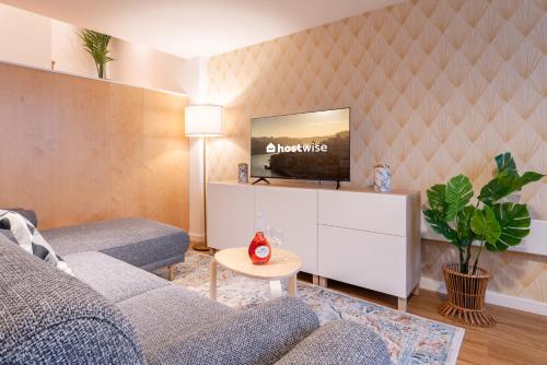 ein Wohnzimmer mit einem Sofa und einem TV an der Wand in der Unterkunft Host Wise - Central Duplex House - Terrace in Vila Nova de Gaia