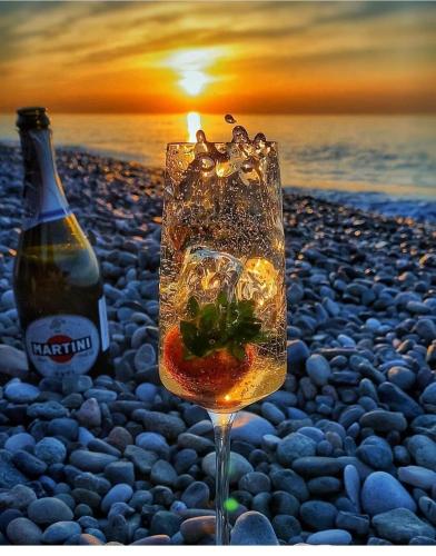 a glass of wine on a beach with a bottle at Vacation Home Nukri in Gonio