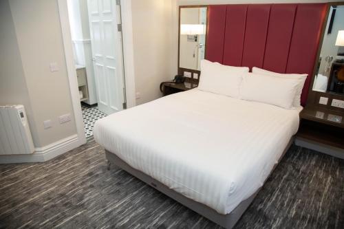 a bedroom with a large bed with a red headboard at Commodore Hotel in Cobh
