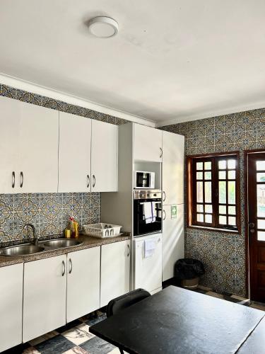a kitchen with white cabinets and a table in it at Asprela Guest House in Porto