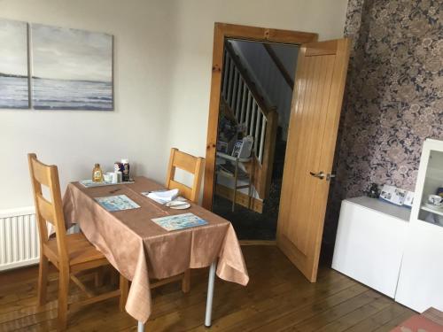ein Esszimmer mit einem Tisch, Stühlen und einer Tür in der Unterkunft Dene House in Great Yarmouth