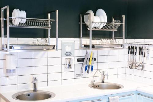 2 Waschbecken in einer weiß gefliesten Küche mit Regalen in der Unterkunft DREAM Hotel Lviv in Lwiw