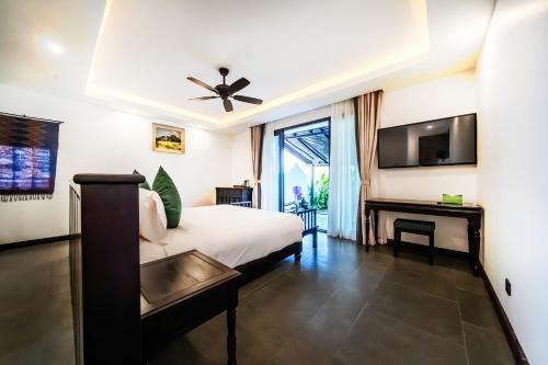 ein Hotelzimmer mit einem Bett und einem TV in der Unterkunft Manyo Hotel and Resort in Luang Prabang