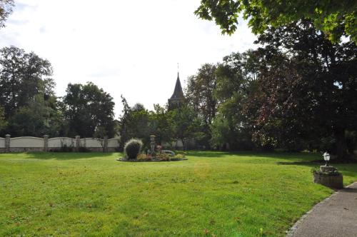 une cour verdoyante avec une église en arrière-plan dans l'établissement Domaine Le Petit Coubert, à Coubert
