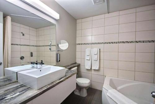 a bathroom with a sink and a toilet and a tub at Travelodge by Wyndham Roberval in Roberval