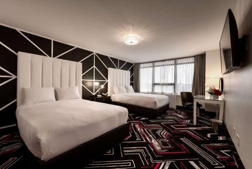 a hotel room with two beds and a desk at Hotel NoMa, Trademark Collection by Wyndham in New Rochelle